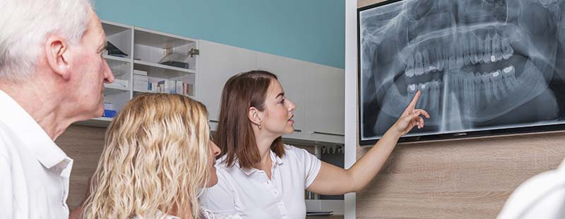 A Patient with her Husband Learning from the Dentist about Dental Implants