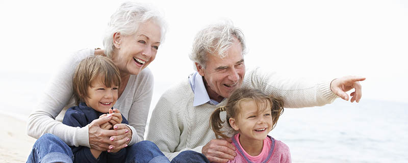 Grandparents Smiling with their Dental Implants at the Beach with their Grandchildren